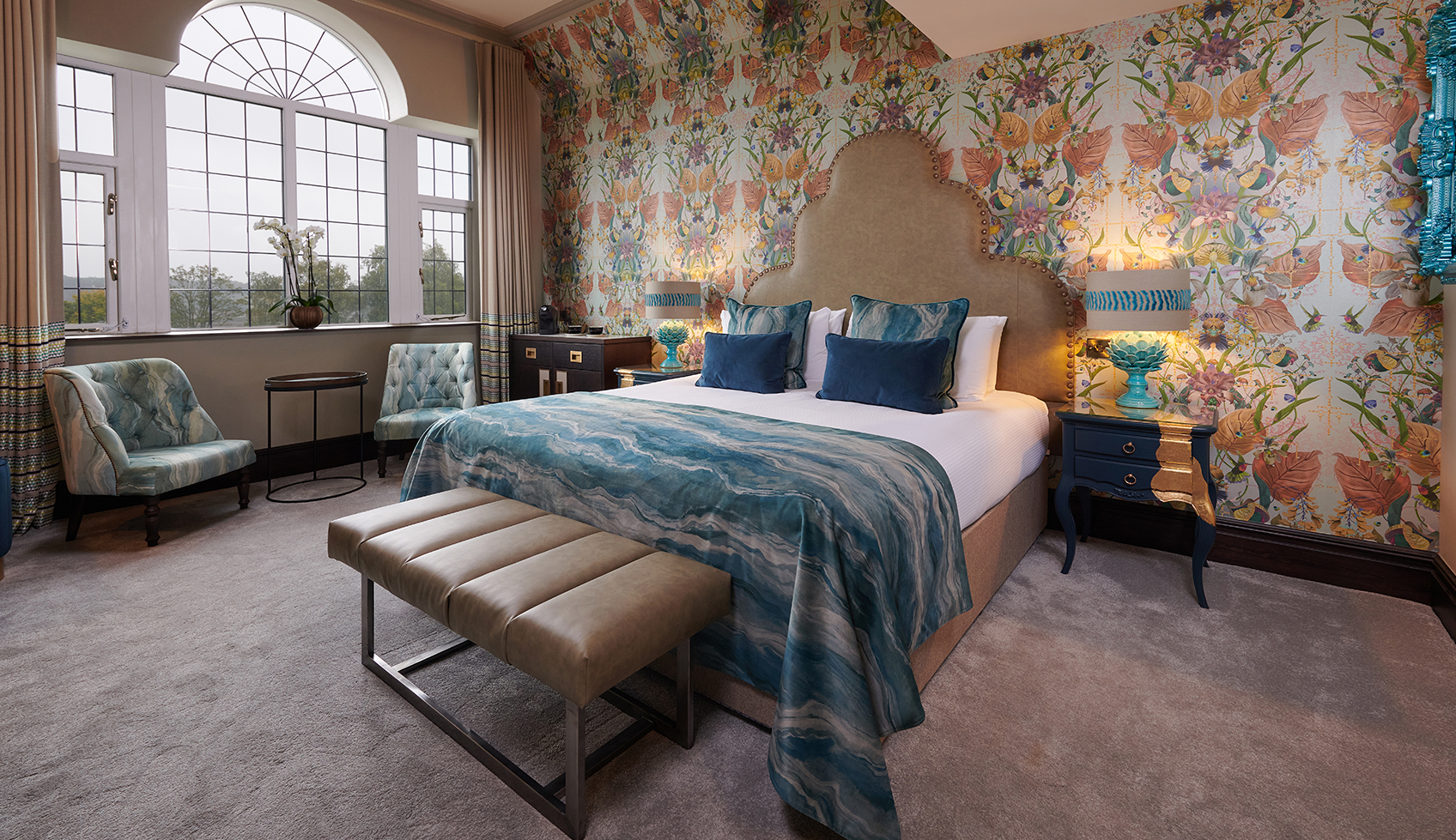 Luxury bedroom with floral wallpaper, blue accents, and large window